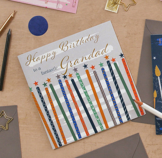 Birthday card for a grandad with colorful candles on a wooden surface