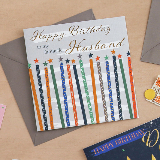 Birthday card for a husband with colorful candles on a beige background