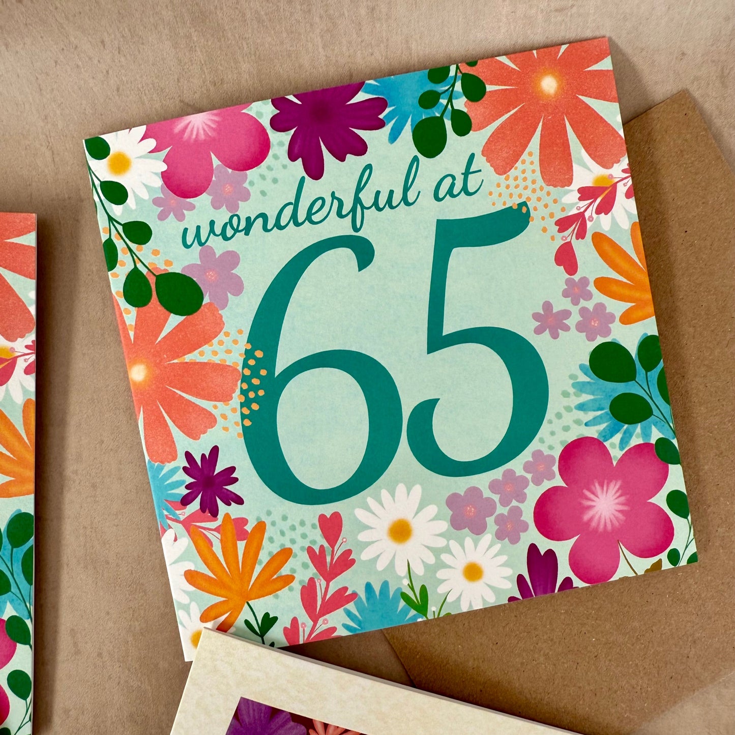 Floral birthday card with 'wonderful at 65' text on a brown background
