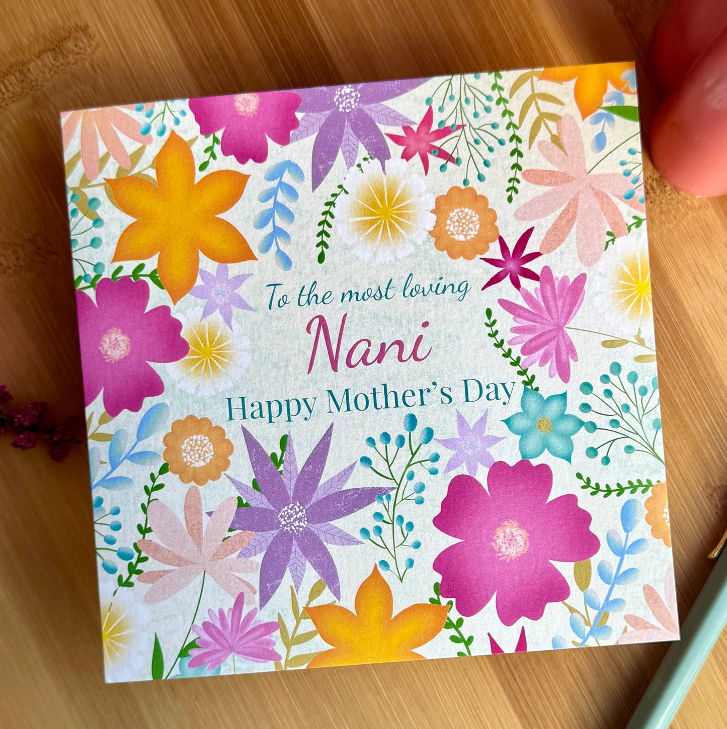 A colorful hand-illustrated greeting card with various flowers and the text 'To the most loving Nani Happy Mother's Day' on it.