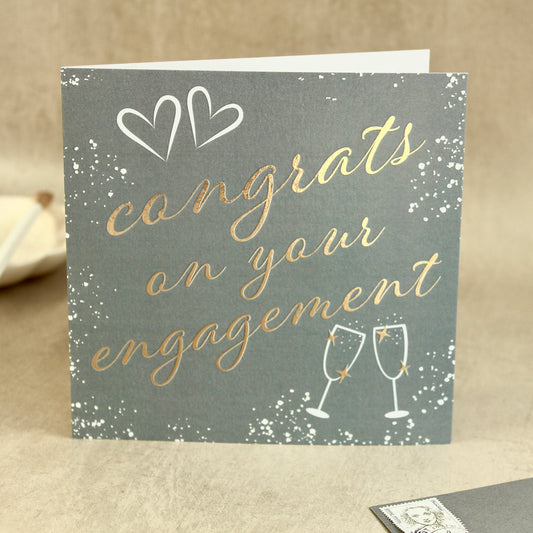 Engagement card with 'congrats on your engagement' text and champagne glasses on a neutral background