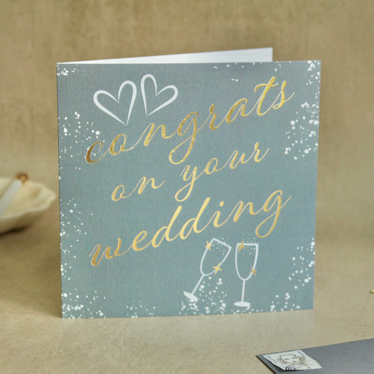 Wedding card with 'congrats on your wedding' text and champagne glass illustrations on a light blue background.