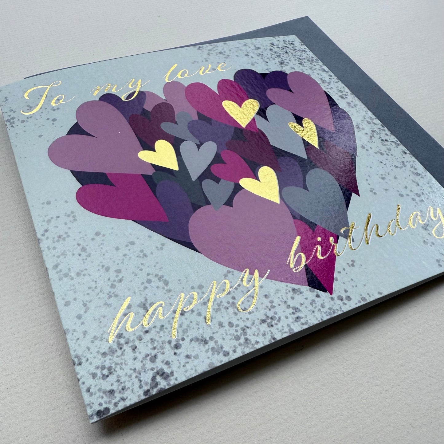 Greeting card with colorful heart design and 'happy birthday' text on a light gray background