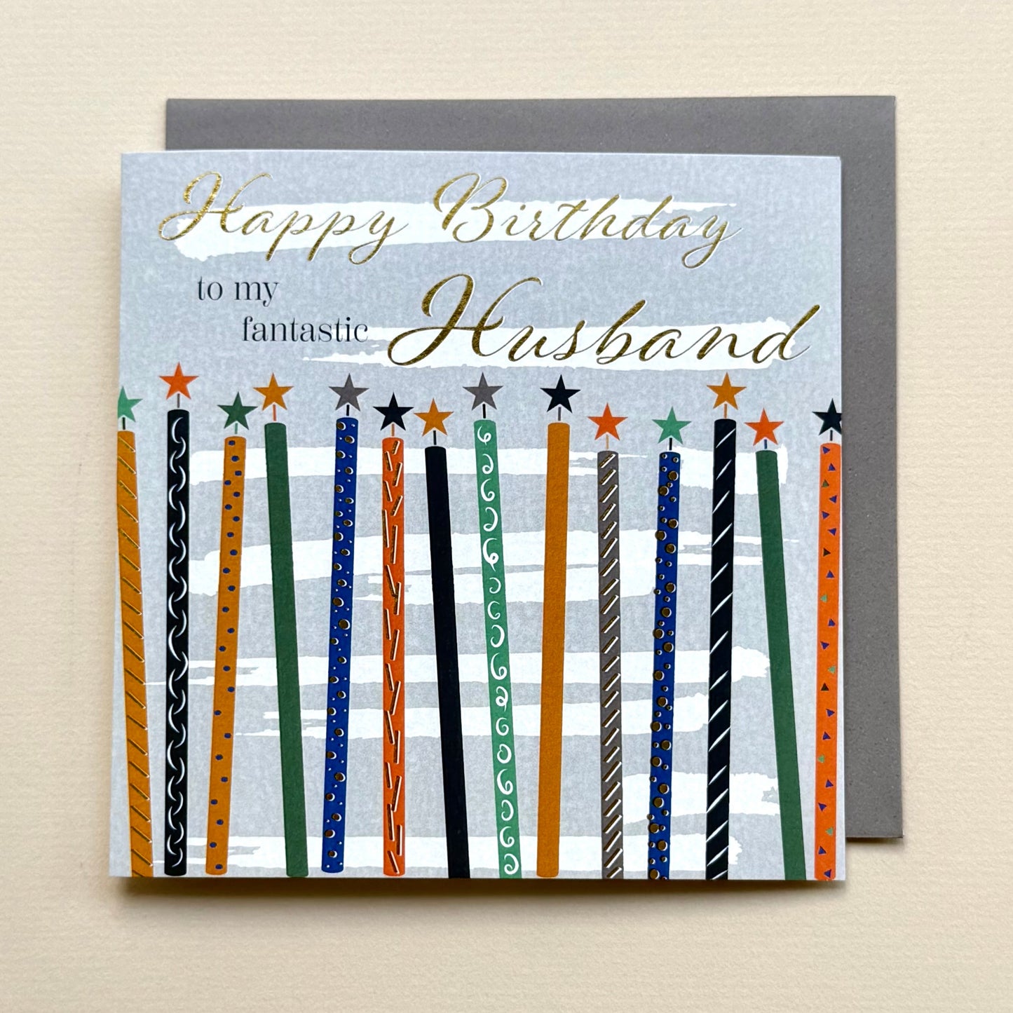 Birthday card for a husband with colorful candles on a light beige background