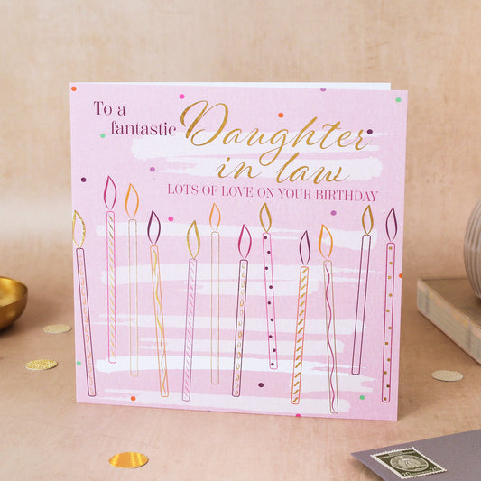 Birthday card for a fantastic daughter-in-law with candles on a pink background, placed on a wooden surface.