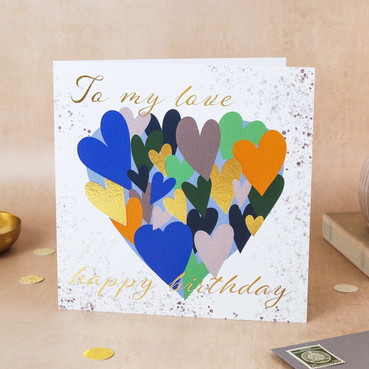 Greeting card with colorful heart design and 'Happy Birthday' text on a wooden surface.