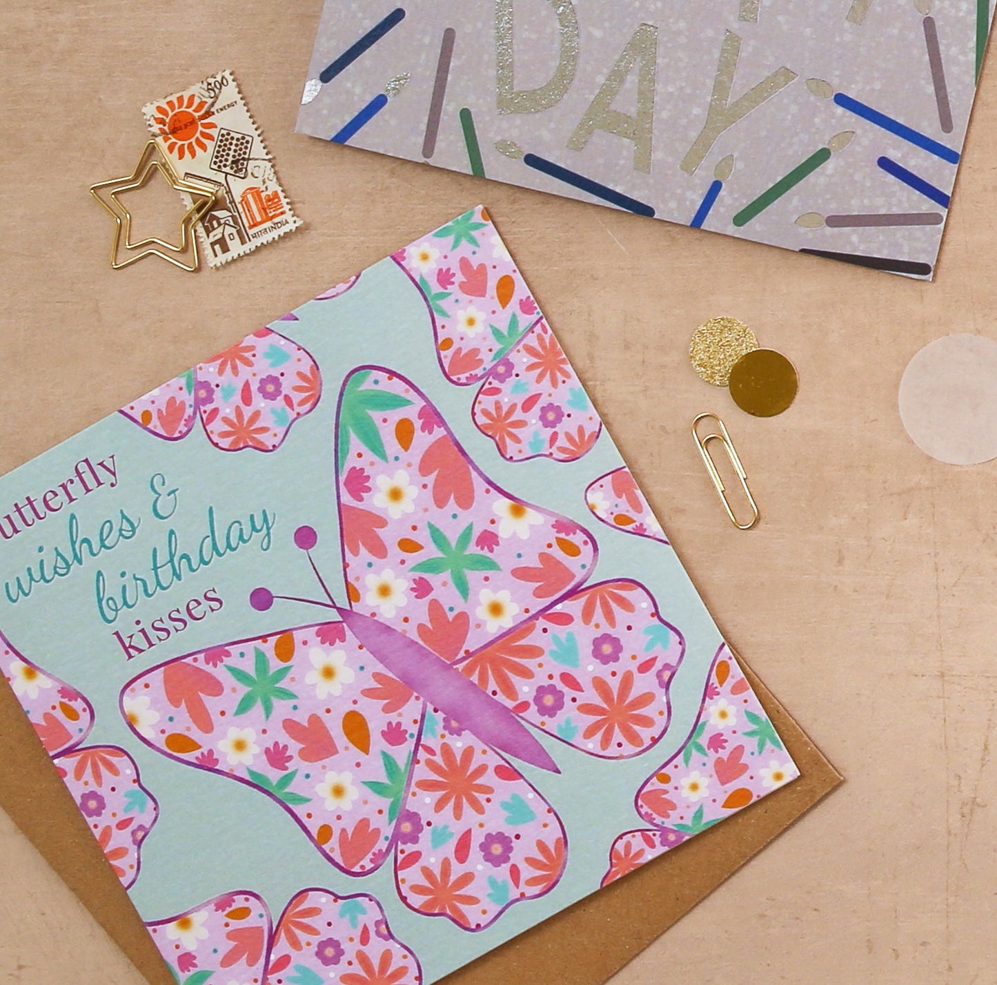 Butterfly-themed birthday card on a wooden surface with decorative items.