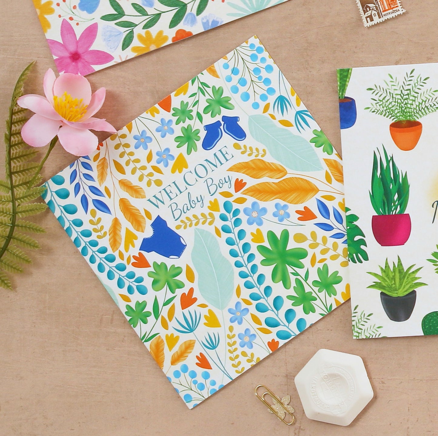 Colorful baby shower card with floral design and text on a wooden surface.