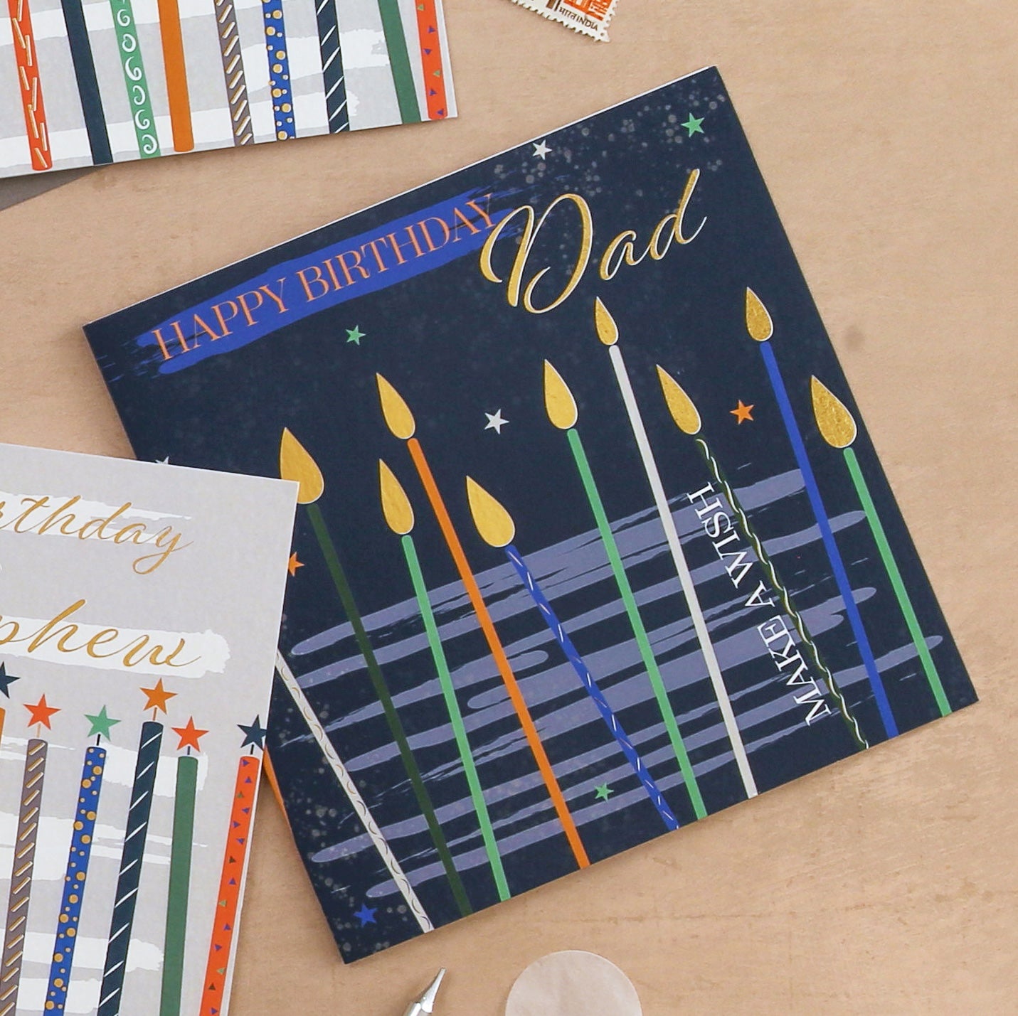 Birthday card with colorful candles and 'Happy Birthday Dad' text on a wooden surface.
