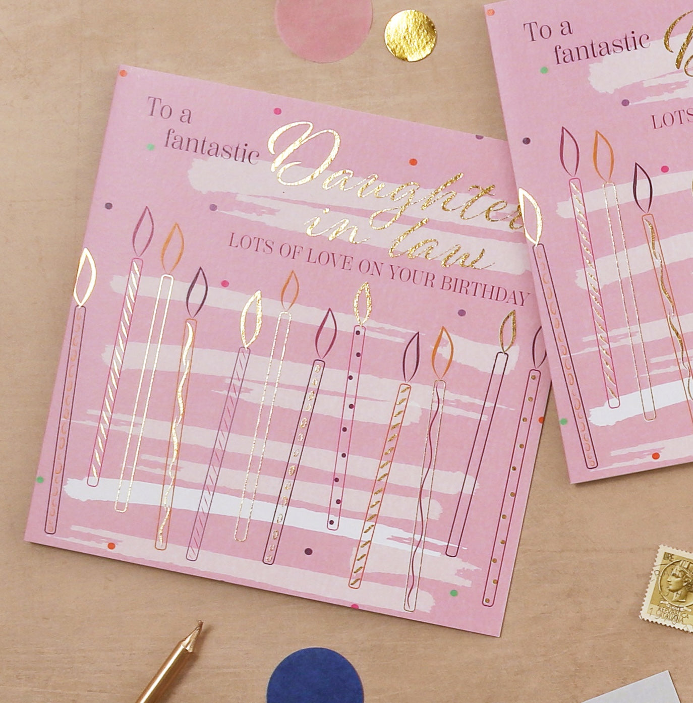 Pink birthday card with candles for a daughter-in-law on a beige surface.