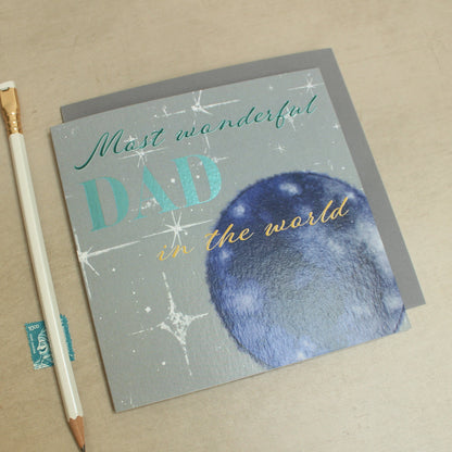 Greeting card with 'Most wonderful dad in the world' text and a pencil on a beige background