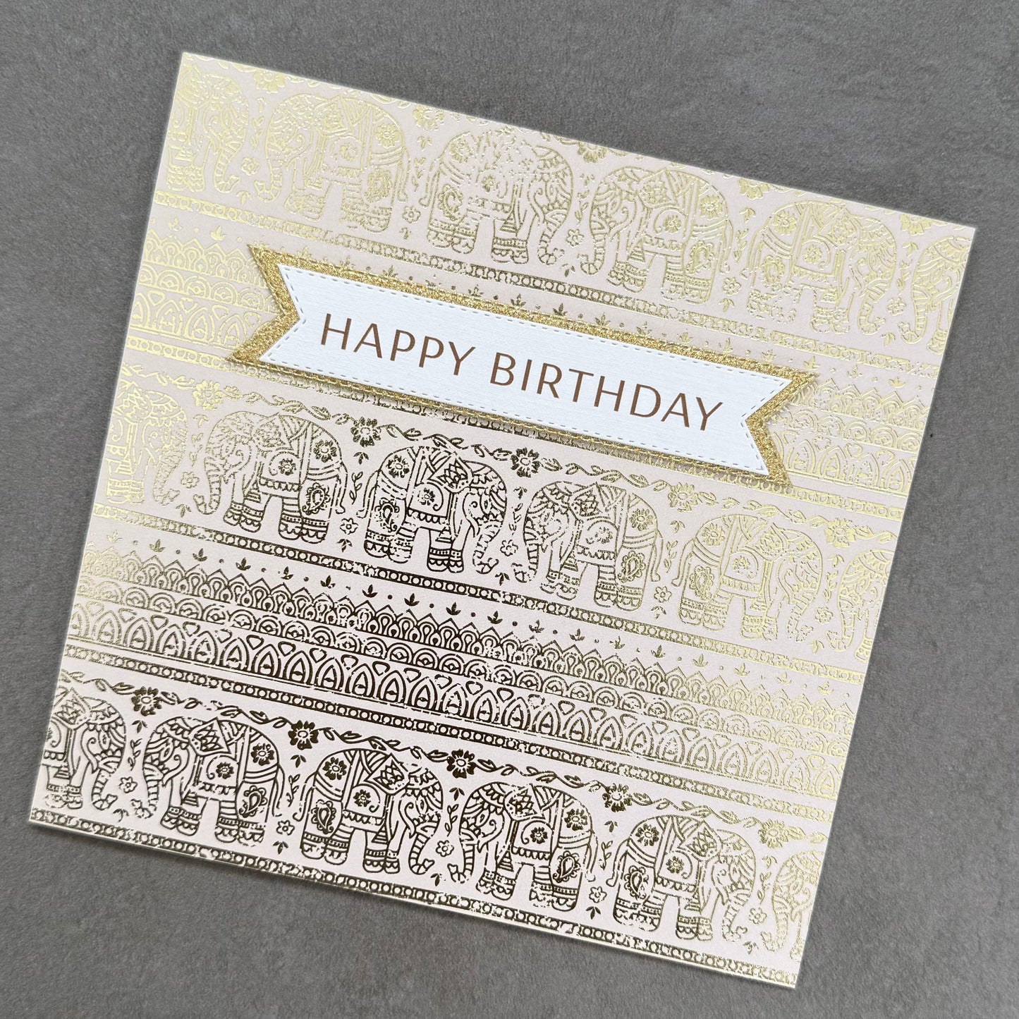 Birthday card with gold and white elephant patterns on a gray background