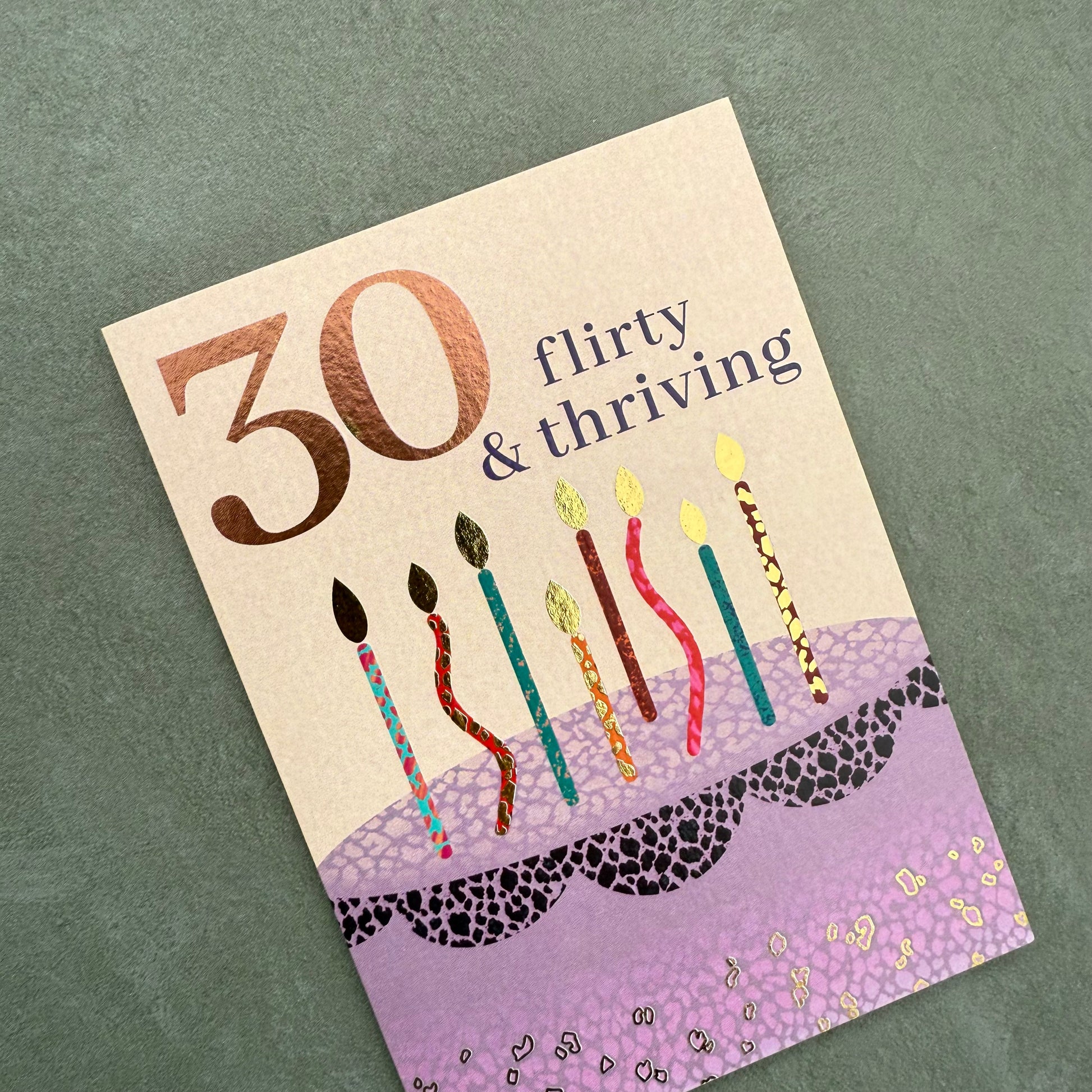 Birthday card with candles and '30 flirty & thriving' text on a textured green background