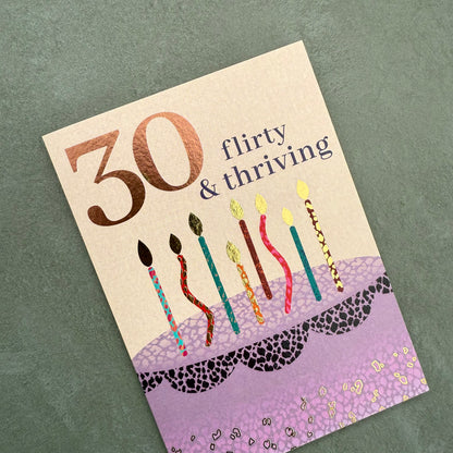 Birthday card with candles and '30 flirty & thriving' text on a textured green background