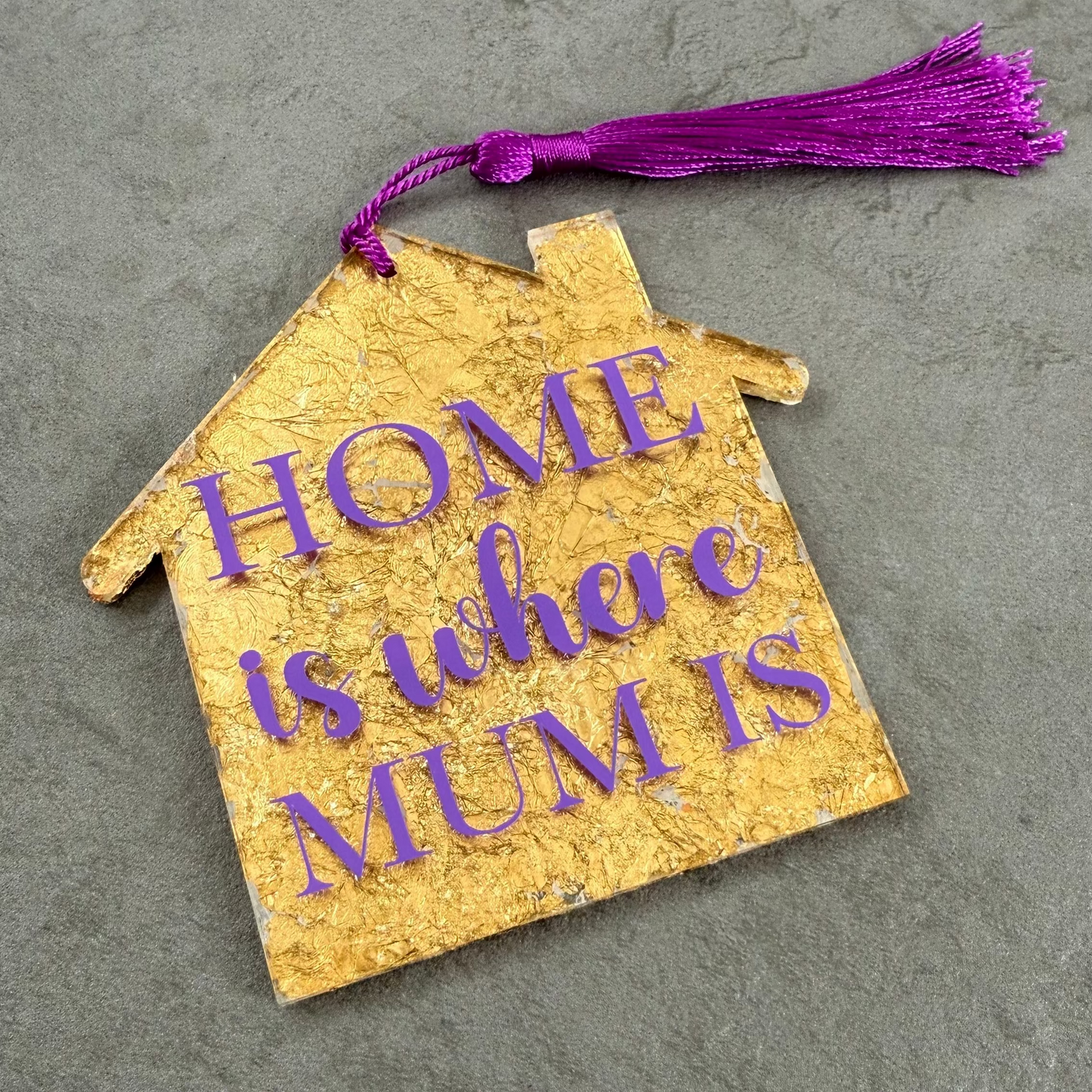 Decorative house-shaped tag with 'Home is where Mum is' text on a textured surface