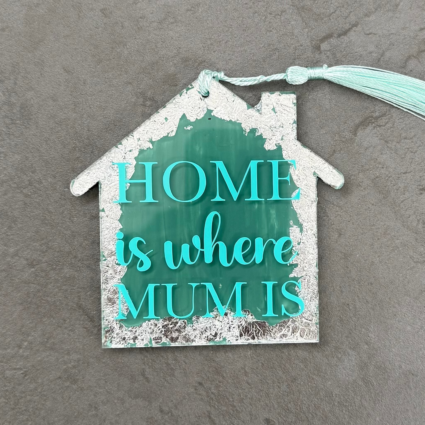 Decorative house-shaped sign with 'Home is where Mum is' text on a gray surface