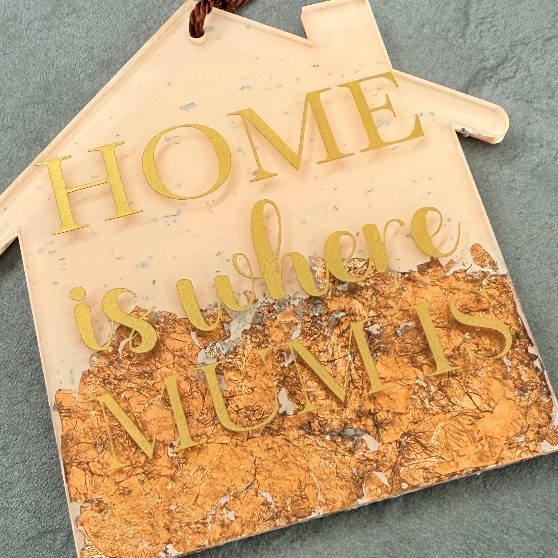 Decorative sign with 'Home is where mum is' text on a textured surface