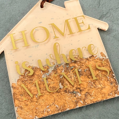 Decorative sign with 'Home is where mum is' text on a textured surface