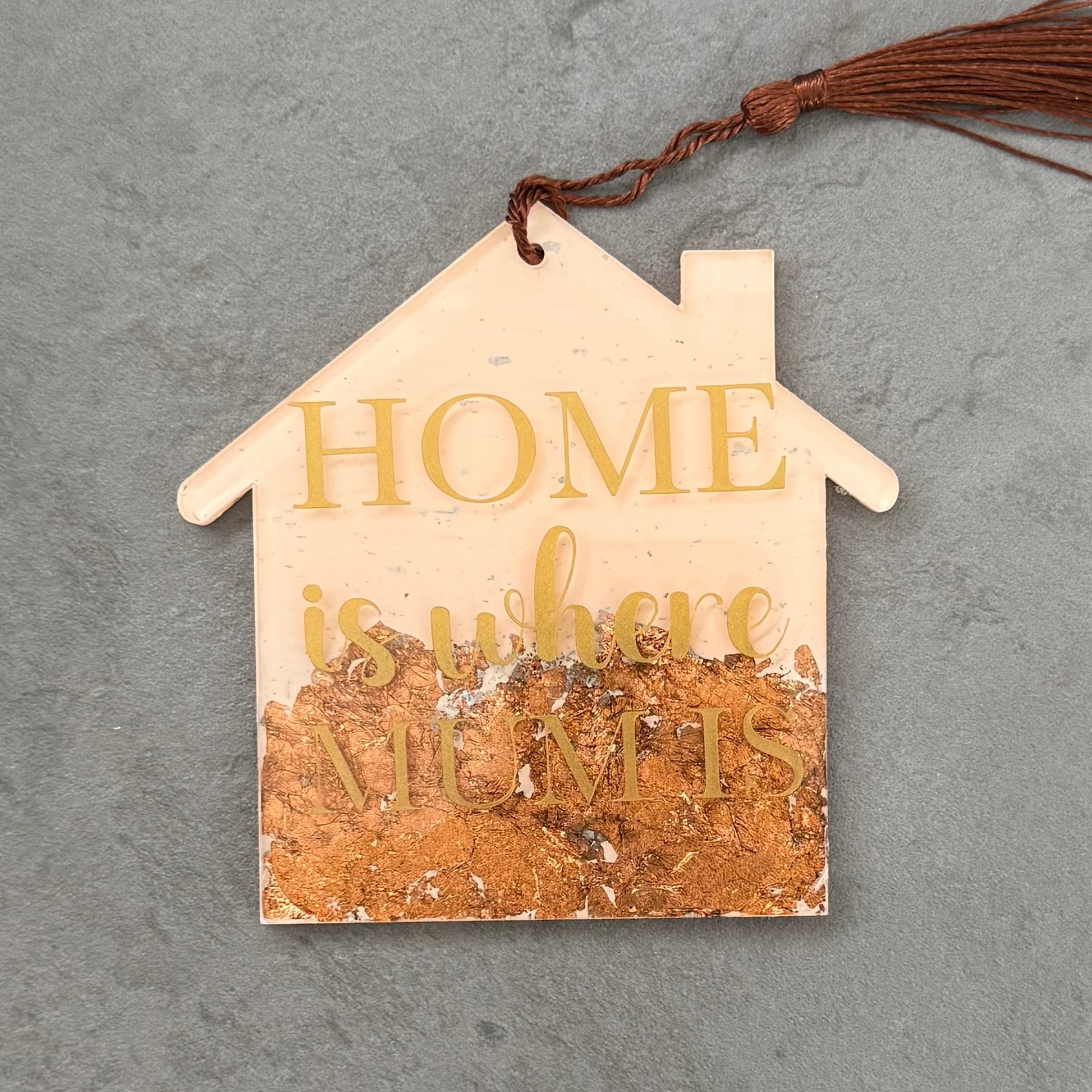 House-shaped wooden ornament with 'HOME is where' text on a gray surface