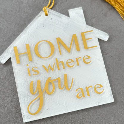 Decorative house-shaped sign with 'HOME is where you are' text on a gray background
