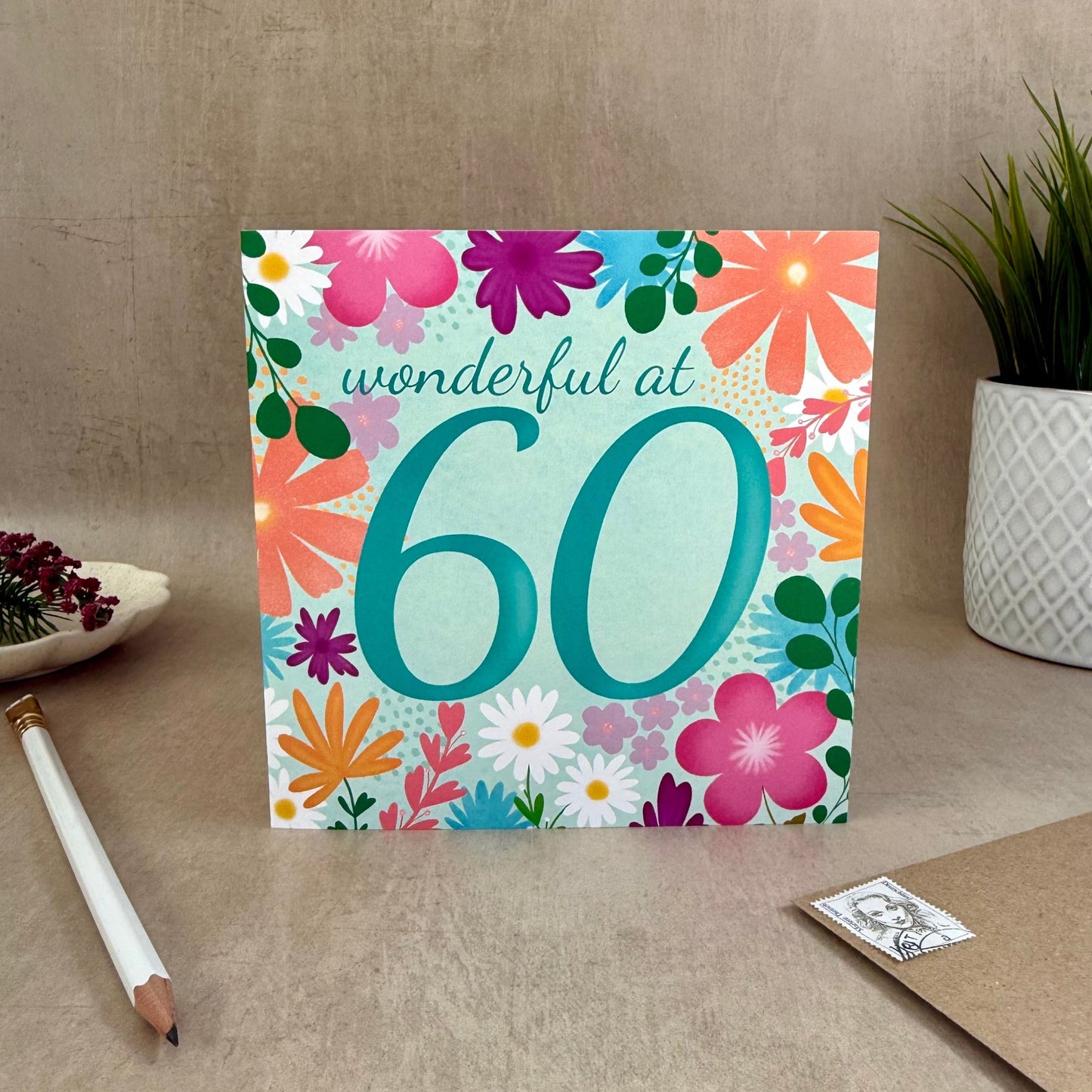 Greeting card with floral design and 'wonderful at 60' text on a neutral background