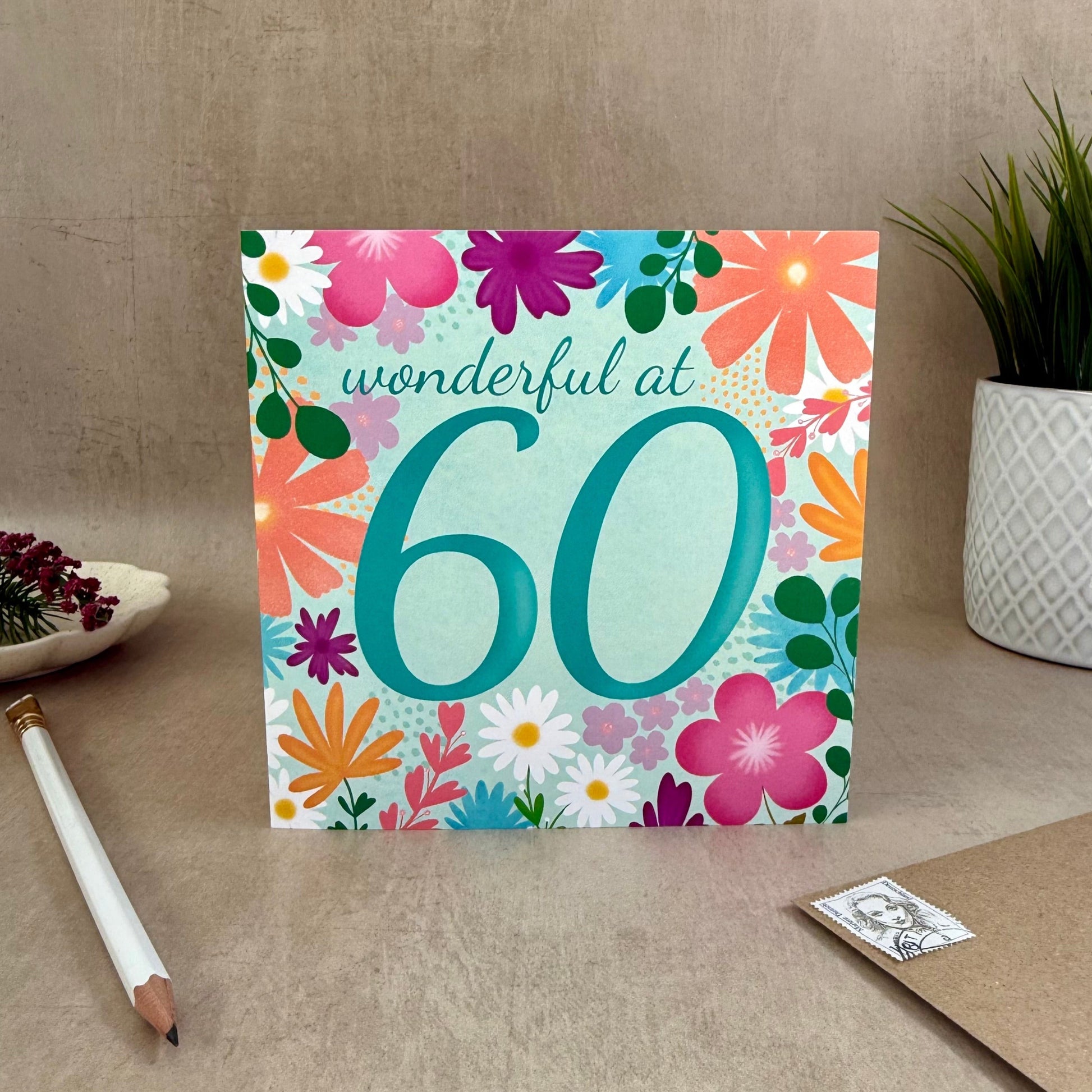 Greeting card with floral design and 'wonderful at 60' text on a neutral background