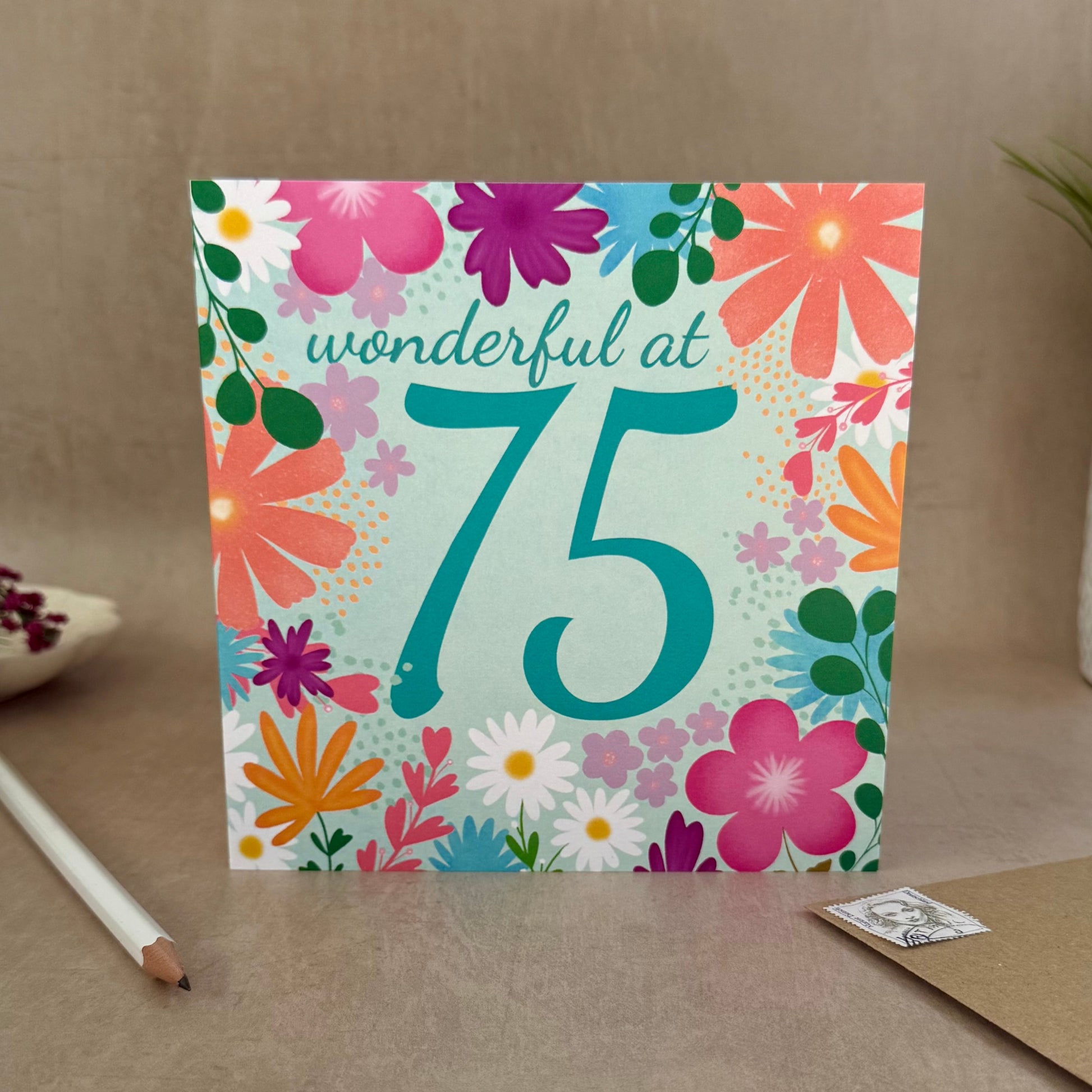 Greeting card with floral design and 'wonderful at 75' text on a neutral background