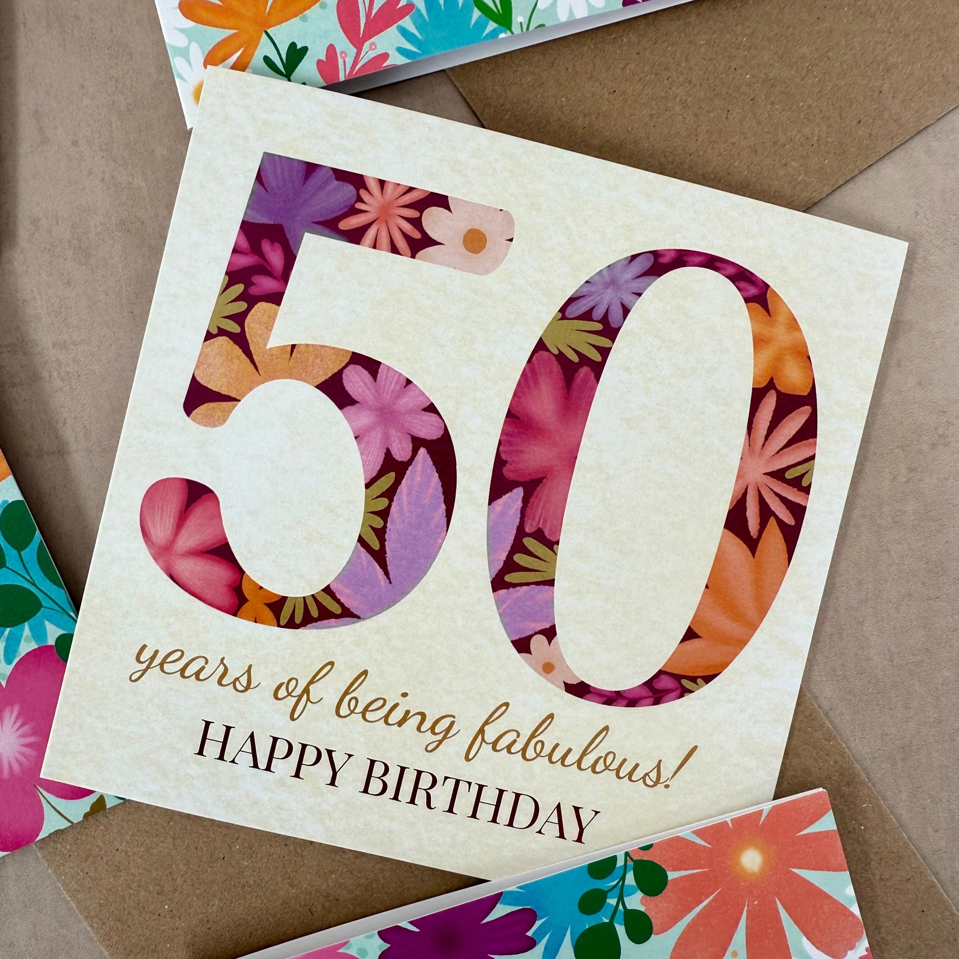Floral birthday card with '50 years of being fabulous! Happy Birthday' text on a brown background.