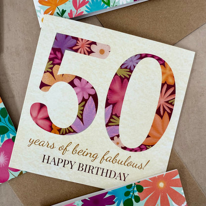 Floral birthday card with '50 years of being fabulous! Happy Birthday' text on a brown background.
