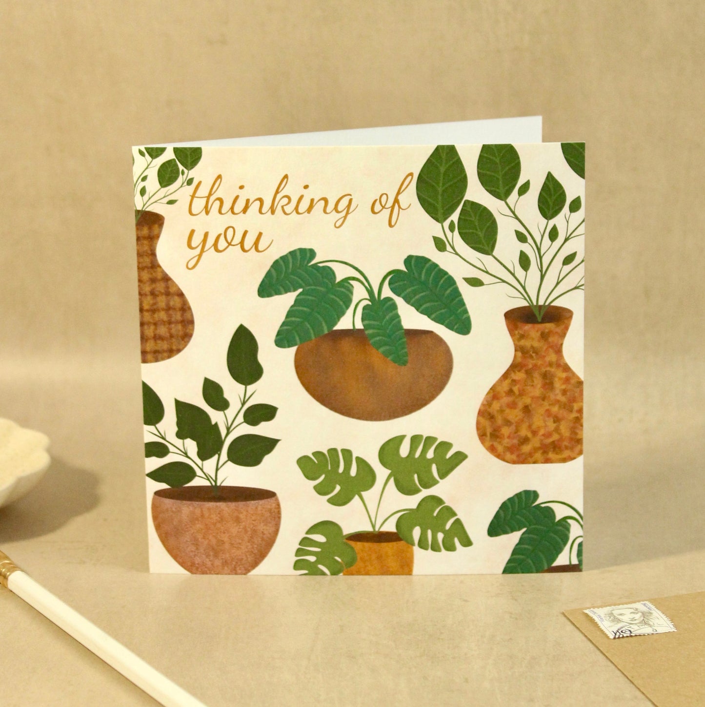 Greeting card with plant illustrations and 'thinking of you' text on a beige background