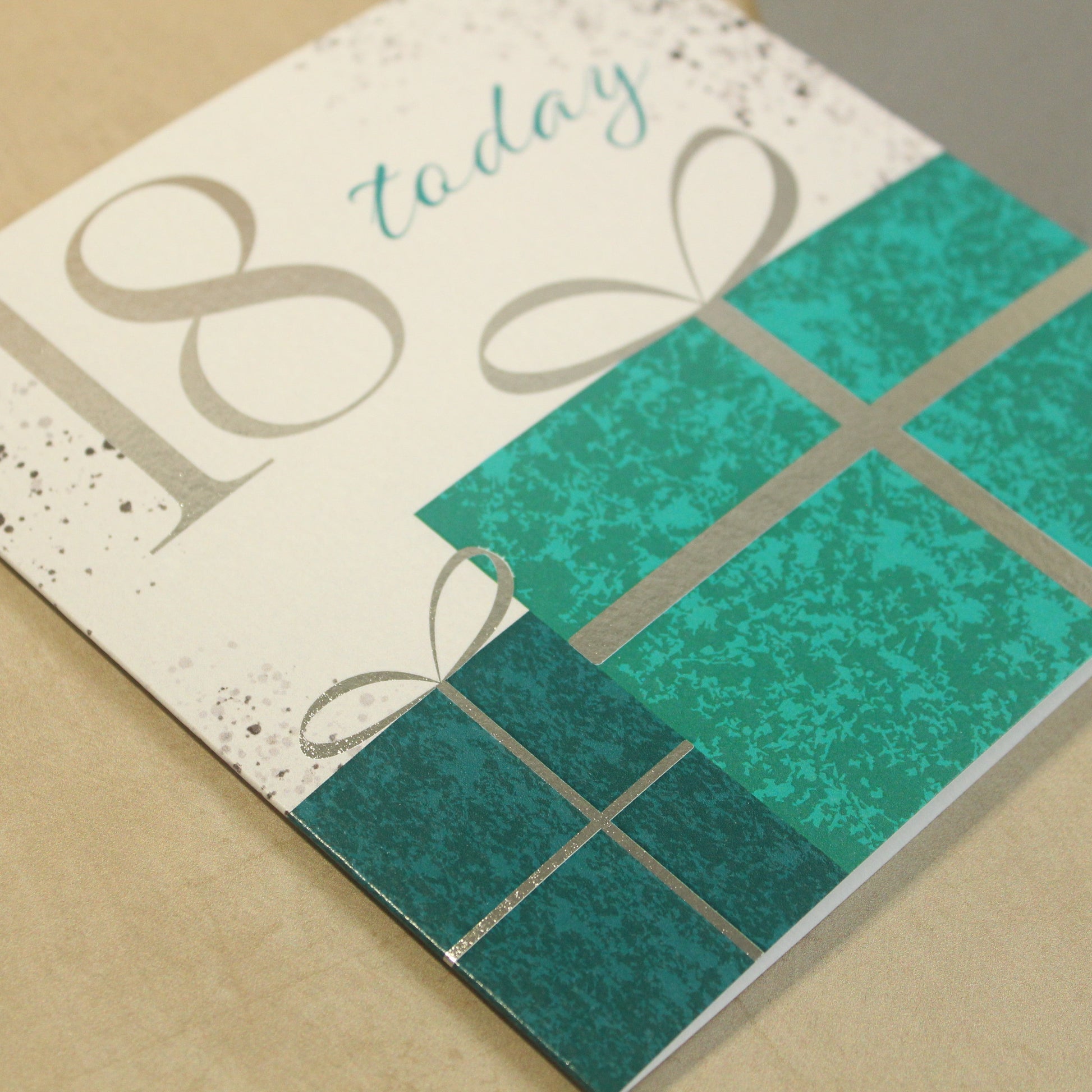 Greeting card with teal present design and '18 today' text on a beige background