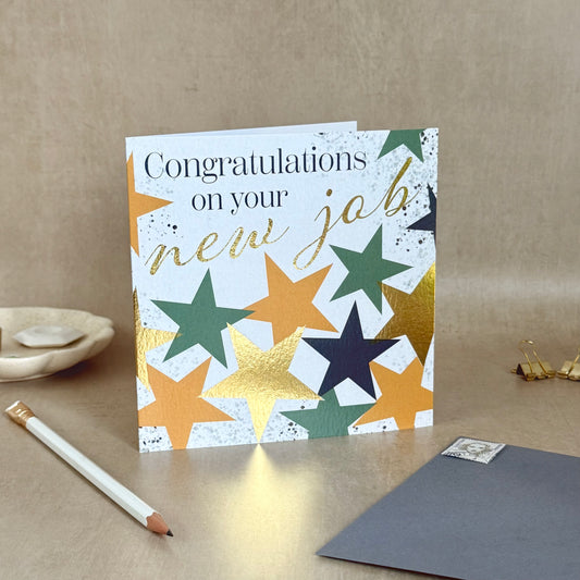 Greeting card with star design and 'Congratulations on your new job' text on a beige surface.