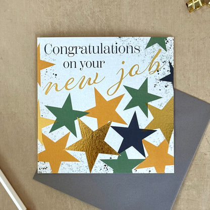 Greeting card with star design and 'Congratulations on your new job!' text on a textured surface.
