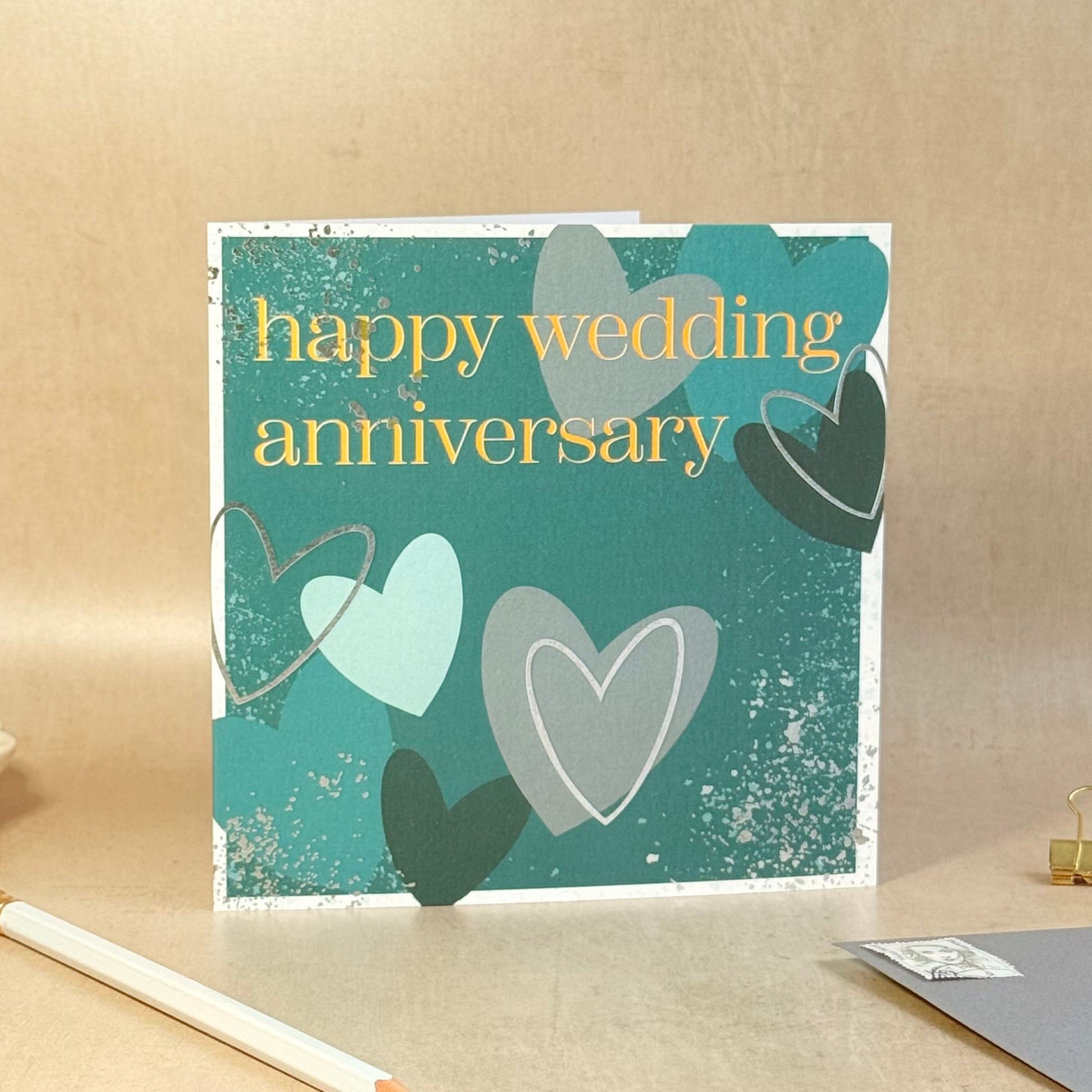 Greeting card with hearts and 'happy wedding anniversary' text on a beige background