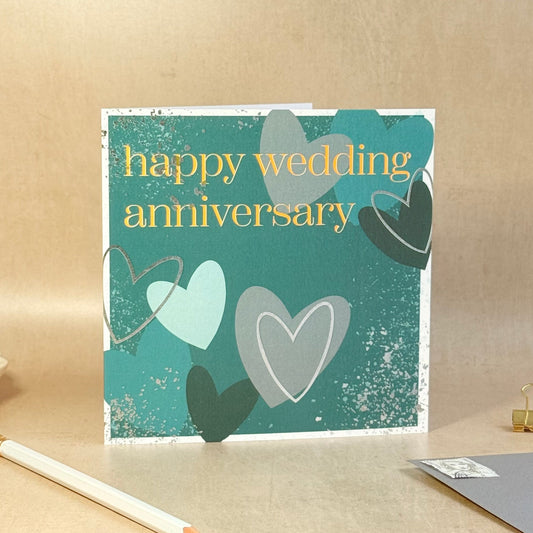 Greeting card with hearts and 'happy wedding anniversary' text on a beige background