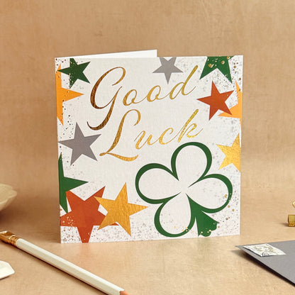 Good Luck card with stars and a clover on a beige surface
