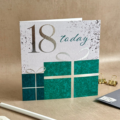 Greeting card with '18 today' text on a textured surface with a pencil and small notebook.