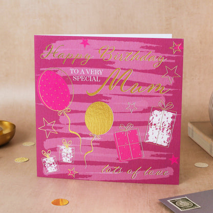 Pink birthday card for a special mum with balloons and presents on a beige surface.