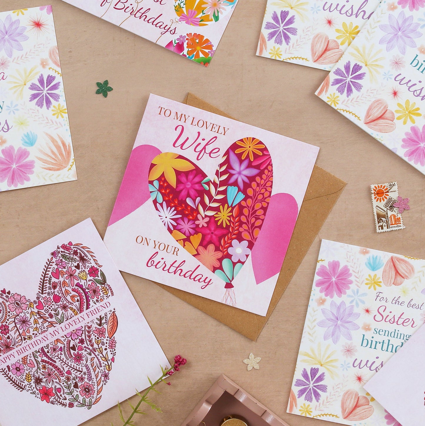 Collection of colorful greeting cards with floral and heart designs on a brown surface.