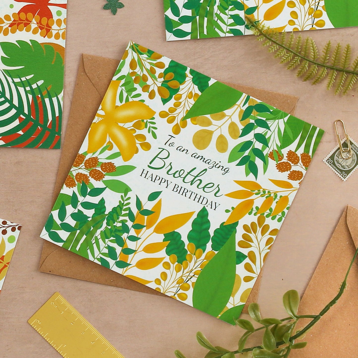 Birthday card with floral design and text on a brown surface with stationery items.