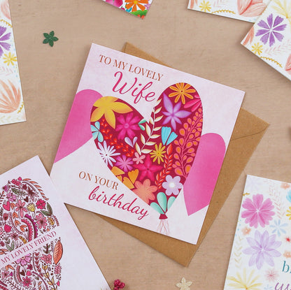 Greeting card with floral heart design and text 'To my lovely wife on your birthday' on a brown surface.