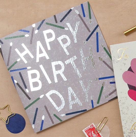 Happy Birthday card with colorful text on a beige surface